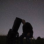 person with telescope and star filled night sky
